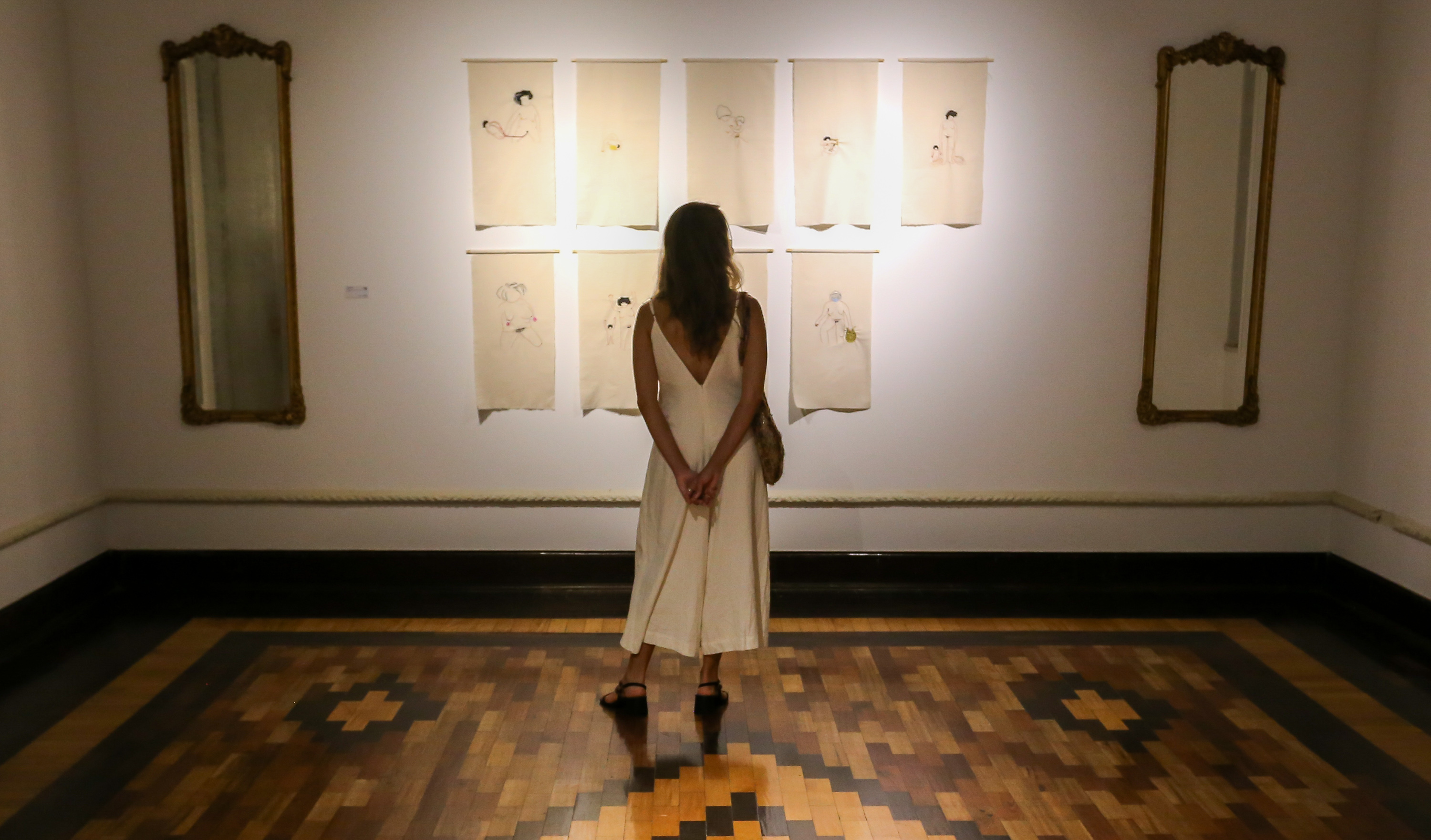 mulher de costas olha uma obra de arte exposta no Salão de Abril